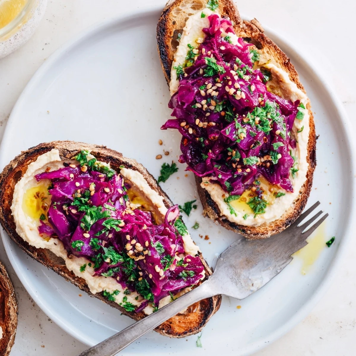 Flavorful pickled red cabbage hummus atop golden toasts, garnished with sesame seeds.