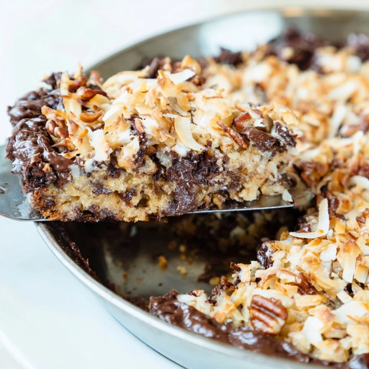 Ein reichhaltiger, klebriger German Chocolate Skillet Cookie mit Kokosnuss-Pekannuss-Topping.  