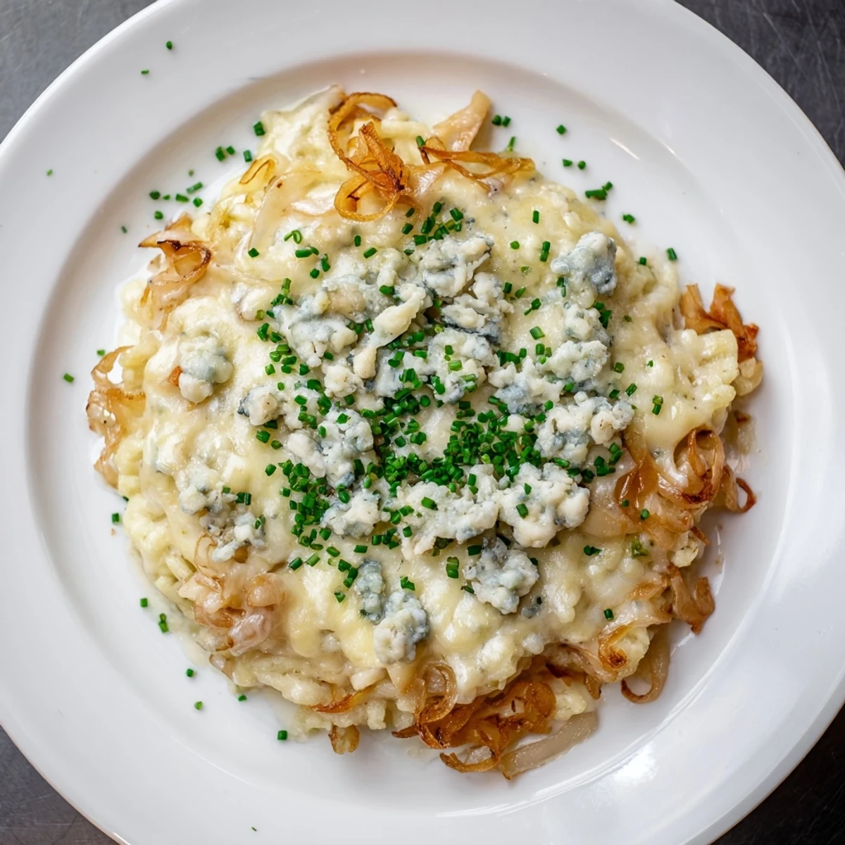 This flavorful Käse-Spätzle Luxus features bubbling cheese, rich Gorgonzola, and sweet caramelized onions.