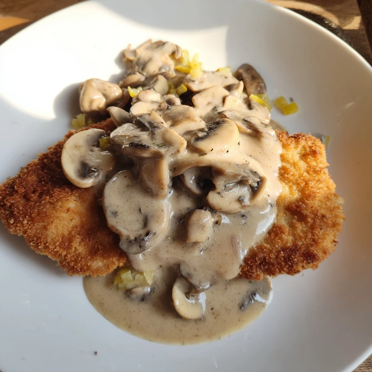 Golden-brown Jaeger Schnitzel sits beneath a rich, creamy mushroom gravy, a hearty German meal.