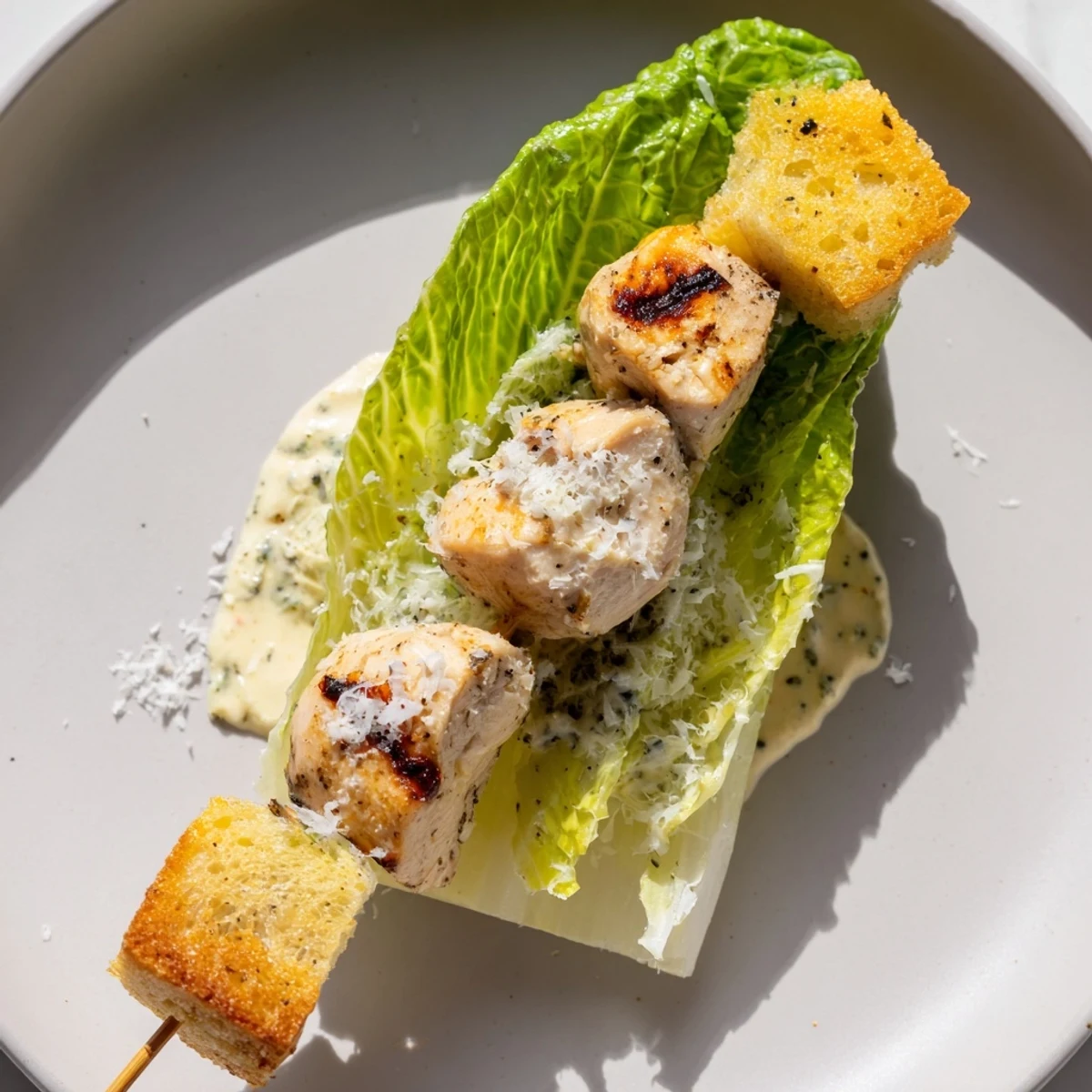 Grilled Chicken Caesar Salad Skewers served with a creamy Caesar dressing and Parmesan cheese garnish.