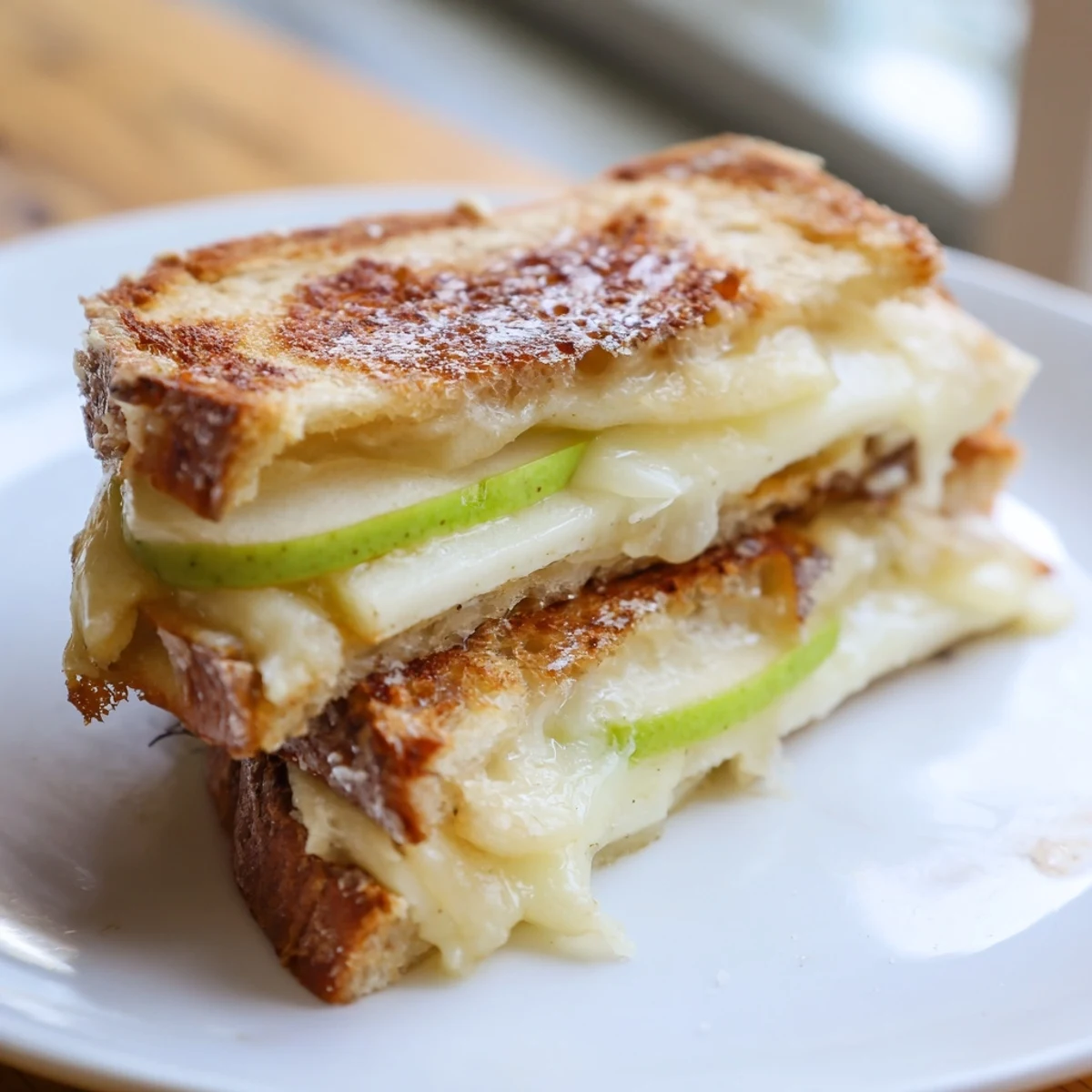 Creamy Brie and apple grilled cheese, oozing melted cheese between toasted sourdough slices with apple.