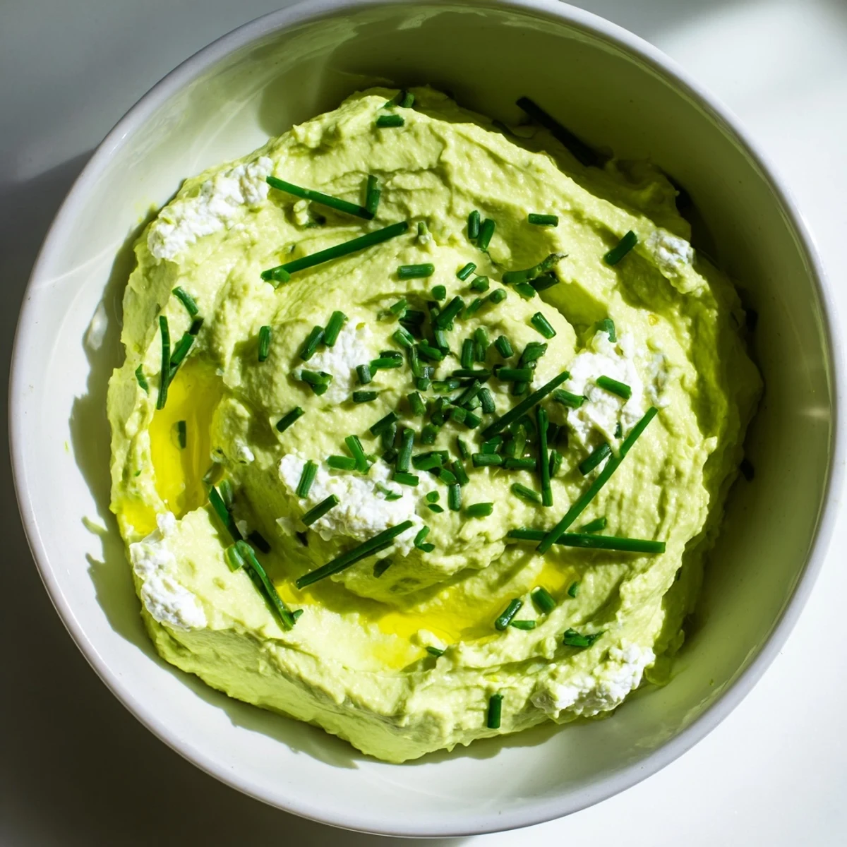 This vibrant photo shows Avocado Cottage Cheese Dip ready to serve with colorful veggie sticks nearby.