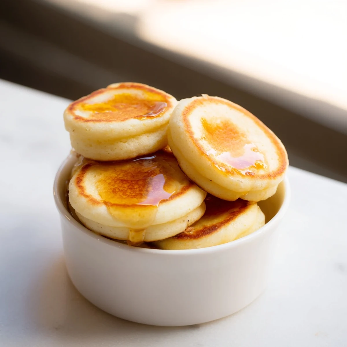 Fluffy pancake cereal served in a bowl, drizzled with maple syrup and creamy milk.