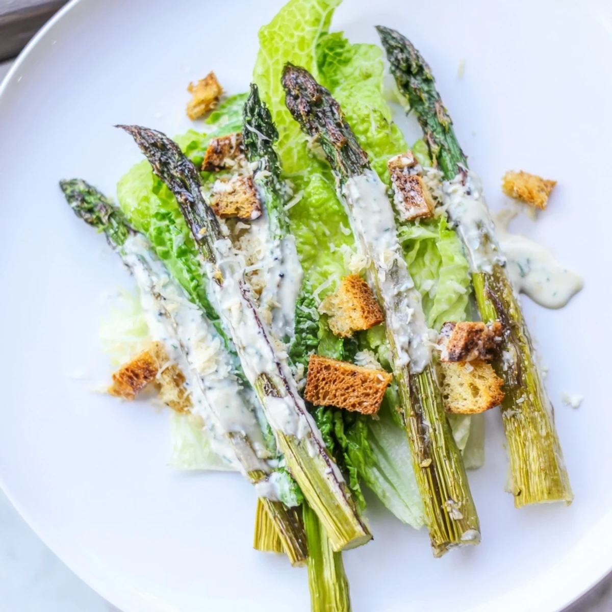 Vibrant photo of Roasted Asparagus Caesar Salad with charred asparagus, crisp romaine, and crunchy croutons.