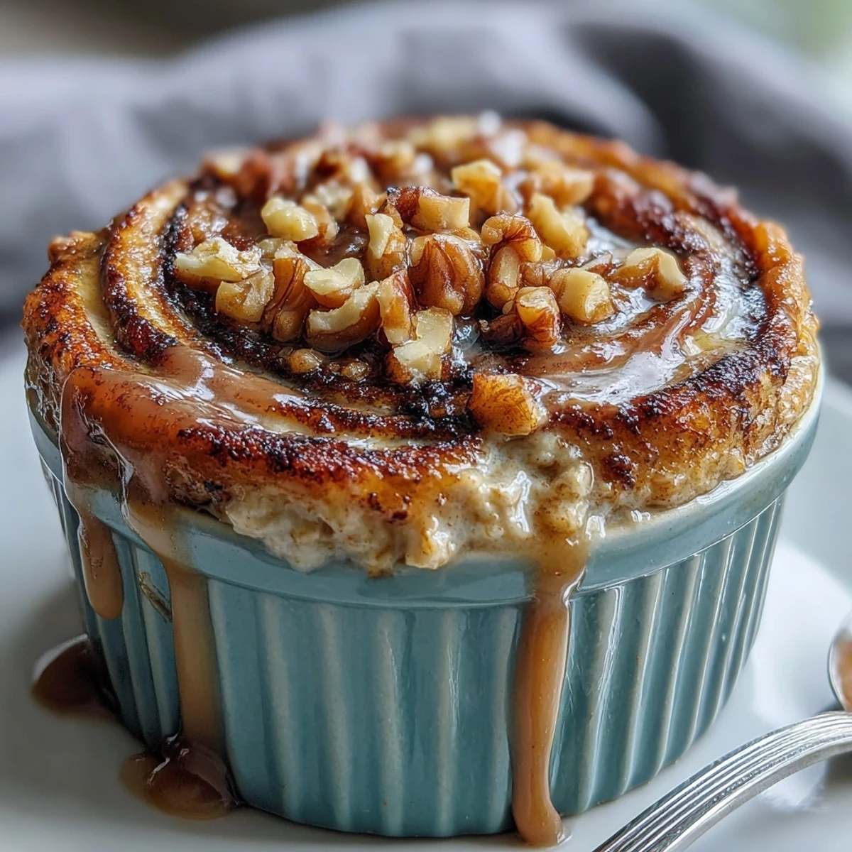 Fluffy Cinnamon Swirl Protein Banana Baked Oats in a ramekin, topped with sliced banana and walnuts.