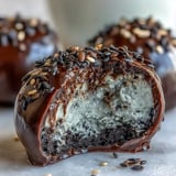 Genieße das Black Sesame Mochi Ice Cream gestapelt auf einer Porzellantasse mit grünem Tee und Eiswürfeln.