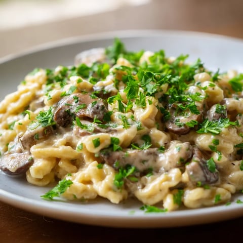 Ein Plate mit Spaetzle, die mit Mushroom Cream garniert sind.