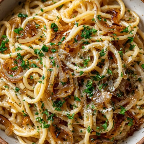 Eine Schüssel mit Pasta, die mit Karamellisierten Zwiebeln und Parmesan garniert ist.