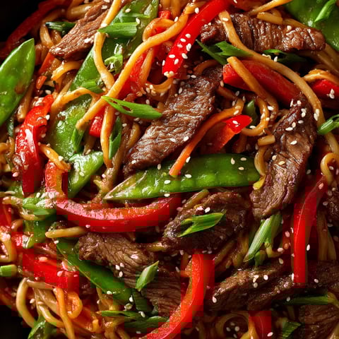 Ein Bild von Sesame Beef Stir-Fry Noodles, das eine Mischung aus Rindfleisch, Sesam und Zwiebeln enthält.