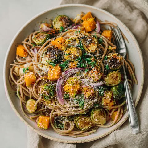 A bowl of pasta with roasted pumpkin and brussels sprouts.