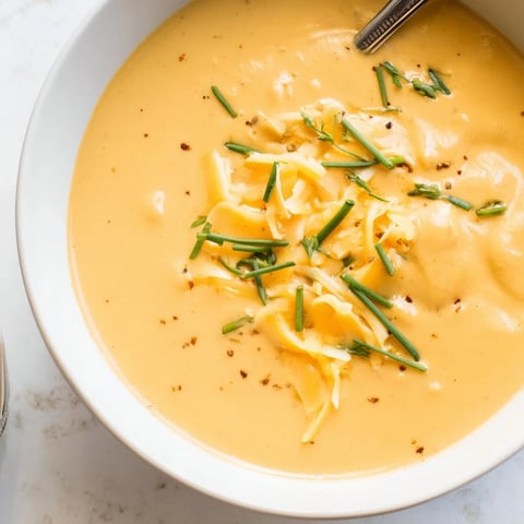 Cremige veganer Bierkäse-Pumpkin-Suppe in einer Schüssel, garniert mit frischen Schnittlauch.  