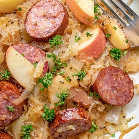 Herzhaftes Sauerkraut- und Wurst-Pfannengericht auf einem rustikalen Holzbrett präsentiert.  