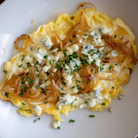 Enjoy a close-up of Käse-Spätzle Luxus with melted cheese and golden caramelized onions.
