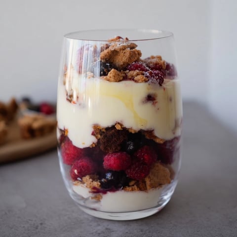 A layered Budget Butterkekse Crumble dessert, showcasing sweet berries, creamy yogurt, and crispy cookie crumbles.