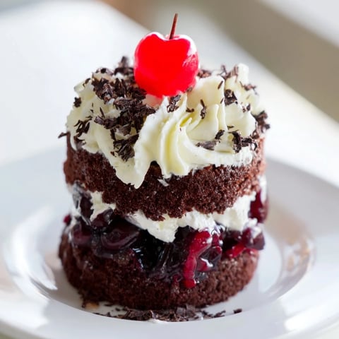 Bite-sized Black Forest cake delights, showcasing layers of cherry filling and whipped cream atop a chocolate cake base.