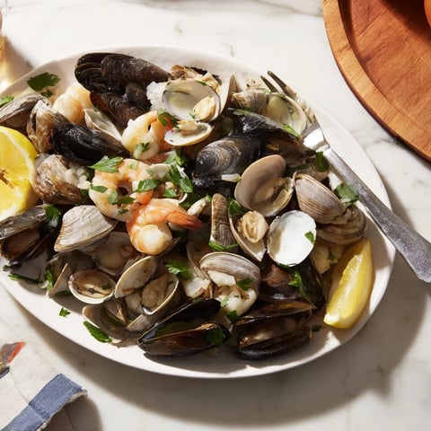 Aromatic Shellfish & Seafood Medley overflowing on a plate, ready to enjoy with lemon wedges.