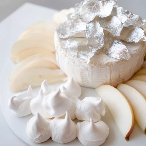 Elegant Pearly Gates cheese board features creamy brie, sweet peaches, crisp meringue, finished with edible silver.