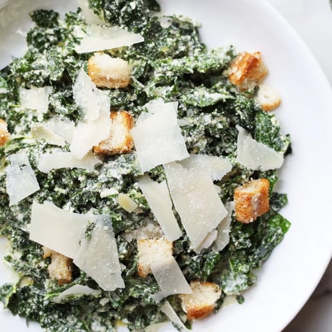 A close-up of a vibrant Kale Caesar Salad, showcasing crunchy croutons and shaved Parmesan.