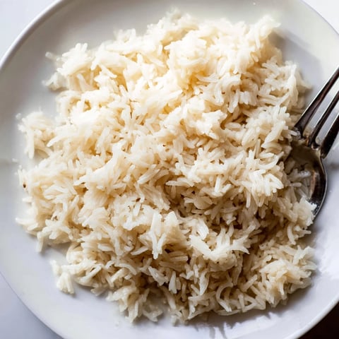 Fluffy coconut jasmine rice glistens, a creamy and aromatic side, ready to complete your meal.