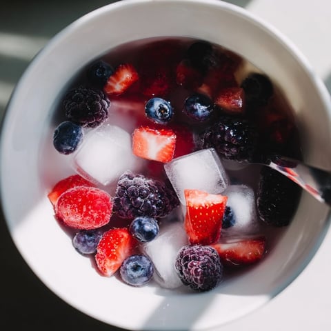 Frische Beeren schwimmen in Kokoswasser in der Natures Cereal Bowl, ein leichter Genuss.