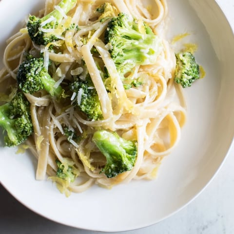 A steaming bowl of one-pot lemon broccoli pasta, garnished with fresh herbs and Parmesan.