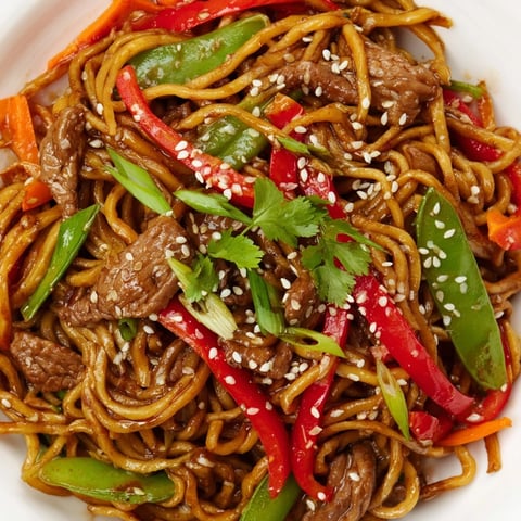 Ein Teller mit Pork Noodle Stir-Fry, wo zarter Pork, knusprige Paprika und Nudeln in einer würzigen Sauce kreiseln.