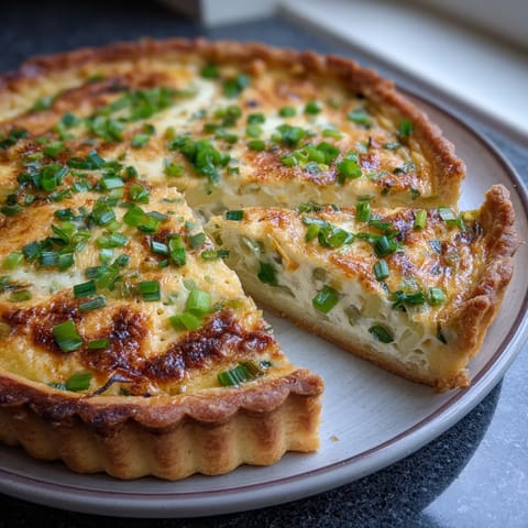 Ein Stück Spring Onion Tart mit Sour Cream auf einem weißen Teller.