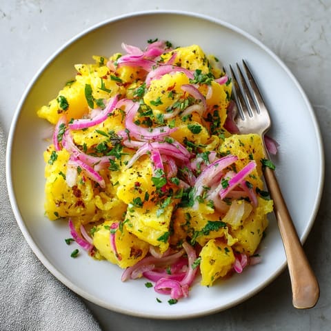 Ein weißer Teller mit saffronen Paprika, piklizierten Zwiebeln und einer Garnitur aus Zwiebeln und Knoblauch.