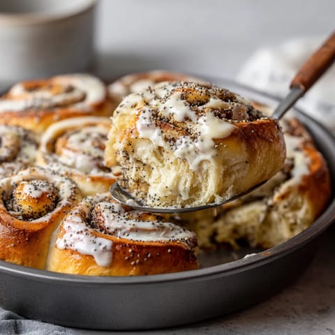 Ein Teller mit Poppy Seed Rolls, die mit weißem Schokolade und Sesamkörnern garniert sind.