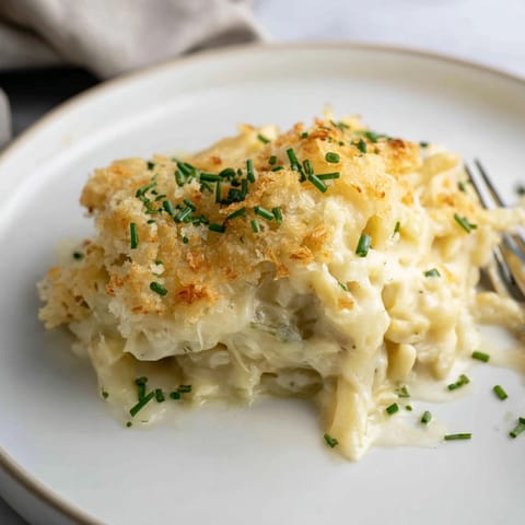 Cremig-käsiger Käse-Spätzle-Auflauf, dampfend serviert, perfekt für einen sättigenden, vegetarischen Genussmoment.