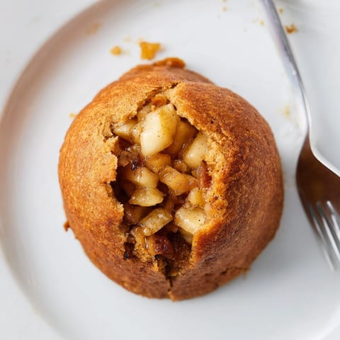 Nahaufnahme von goldbraunen, hausgemachten Rustic Rye & Apple Dumplings, bereit zum Servieren mit Vanillesauce.