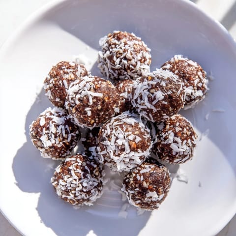 Schokoladige Energy Bites mit Datteln, gerollt in Kokosnuss, ein köstlicher, schneller, veganer Snack.
