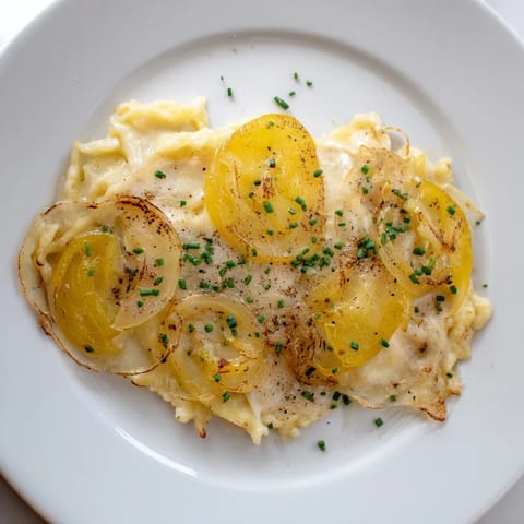 Close-up of baked Käsespätzle: a comforting German pasta with melted cheese and herbs.