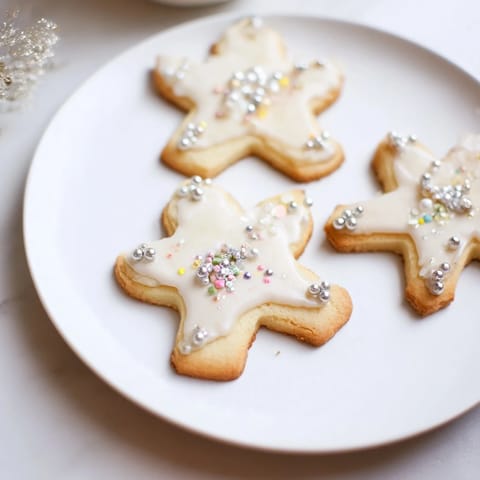 Golden baked Biscuits Anges de Noël, dusted with icing and sprinkles on a festive plate.