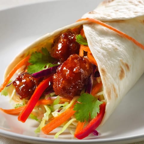 Close-up of a flavorful Honey Sriracha Chicken Wrap, showing the sauce on the chicken.