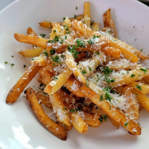 Close-up of freshly made Truffle Parmesan Fries, with salty Parmesan and herbs, delicious side dish.