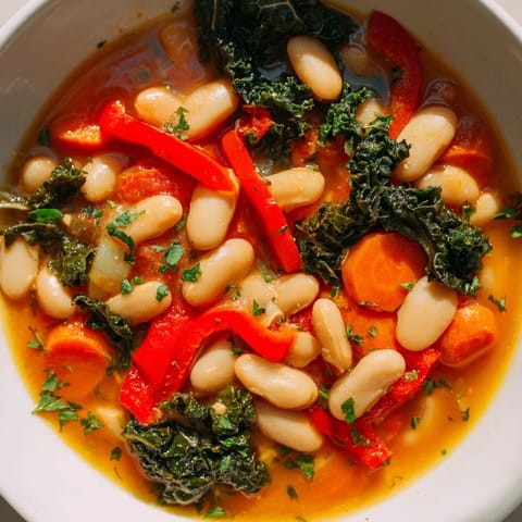 A hearty Mediterranean White Bean Stew served in a rustic bowl, garnished with parsley and lemon wedges for brightness.  