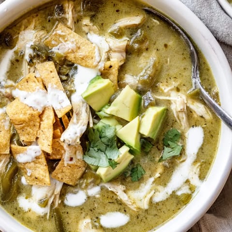 Cremige Hühnchen-Tortilla-Suppe mit salsa verde Basis, Poblanos und Jalapeños, garniert mit cremigem Avocado und knusprigen Tortilla-Chips.