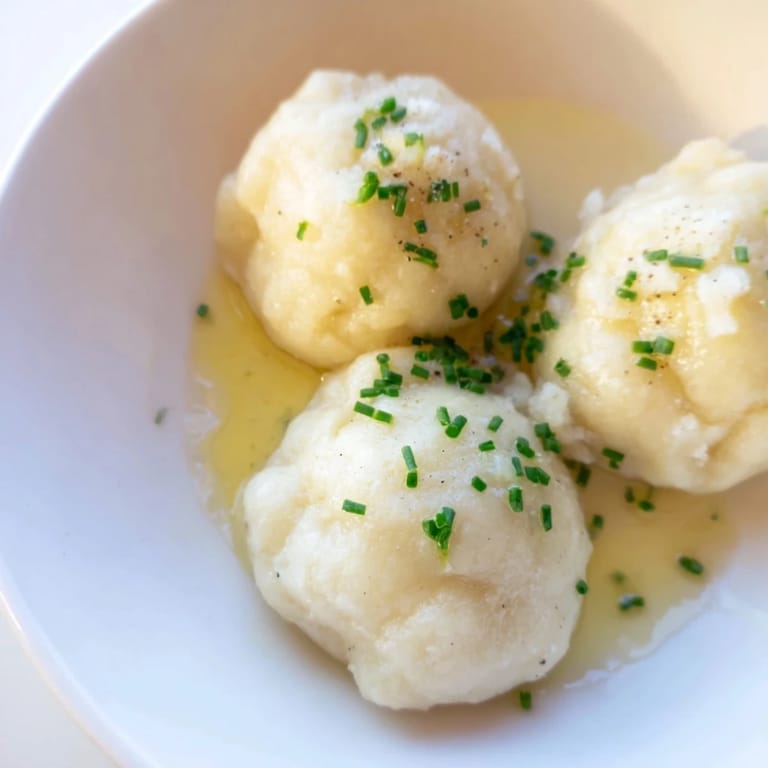 A serving of golden-brown potato dumplings, swimming in butter and truffle oil, ready to be enjoyed.
