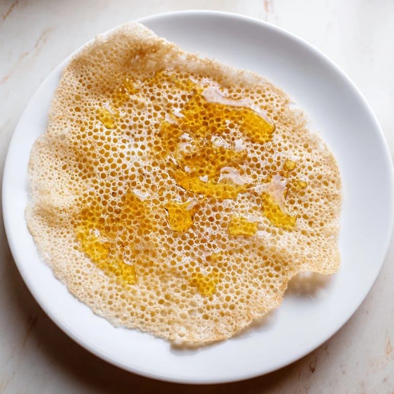 Warm, honeycomb-textured Moroccan Baghrir, served drizzled with glistening honey and melting butter.