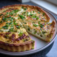 Ein Stück Spring Onion Tart mit Sour Cream auf einem weißen Teller.
